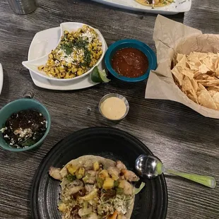 One octopus taco with side of black beans, Elote appetizer, grilled fish taco, chips and salsa.