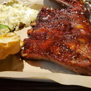 a plate of ribs, potatoes, and coleslaw