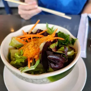 a bowl of salad and chopsticks
