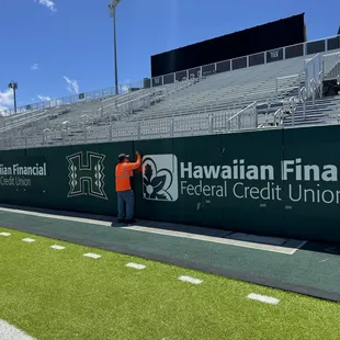 Banners installed at University of HI football stadium for sponsor advertising.