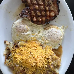 One pork chop and two eggs, home fries smothered with chili and cheese