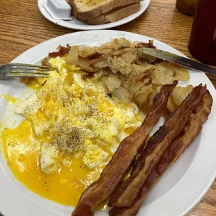 a plate of eggs, bacon and toast
