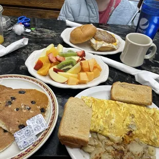 Western omelette, blueberry pancakes, fruit plate, and sausage egg and cheese sandwich