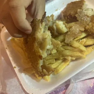 a hand picking up a piece of fish and chips