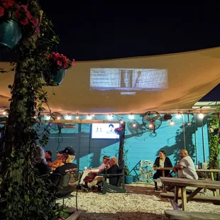 people sitting at tables under a shade