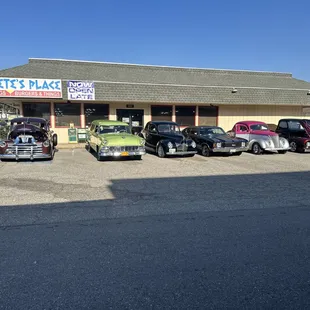 a row of classic cars parked in front of a building