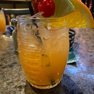 a glass of orange juice with a cherry on top