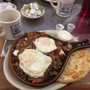 Greek Skillet with two eggs over easy and pita bread.