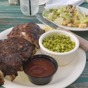 Dry ribs w BBQ sauce on the side, w Caesar Salad and peas.