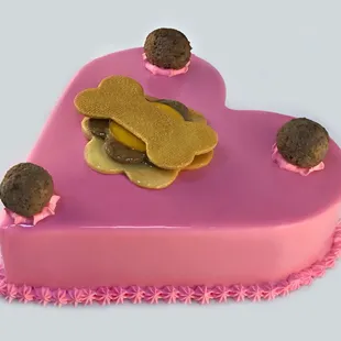 a pink heart shaped cake with a dog bone on top