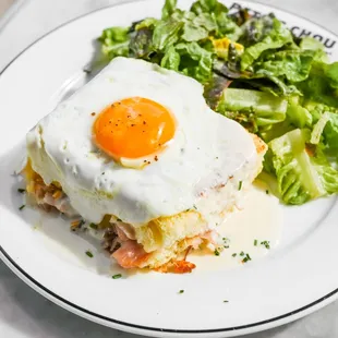 Croque Madame: Thinly sliced ham, gruyère, mornay, chives, topped with an egg and served with a side of lightly dressed greens!
