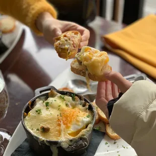 a person holding a piece of bread over a bowl of food