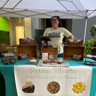 a woman standing behind a table with a display of cookies