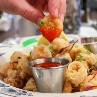 a person dipping a piece of food into a bowl