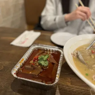 a woman eating a bowl of soup with chopsticks