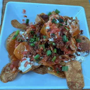 Clubhouse chips - house made kettle chips covered in blue cheese fondue, crumbled bacon, diced tomatoes and green onions, and hot sauce