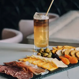 a platter of meat, cheese, olives, and crackers