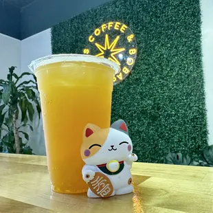a glass of orange juice and a cat figurine