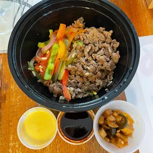 Beef fried rice bowl with two sauces and a delicious Korean side dish of pickled vegetables.