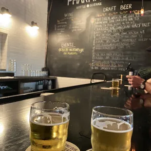 two glasses of beer on a bar