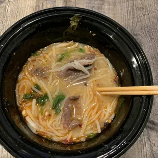 a bowl of soup with chopsticks