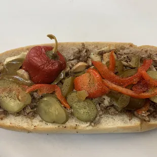 Cheesesteak with hot peppers, sweet peppers, and pickles.