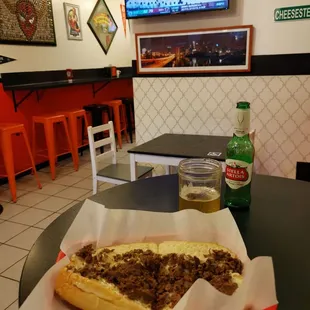 a table with a hot dog and a bottle of beer
