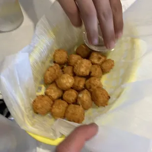 a person placing a piece of chicken nuggies in a basket