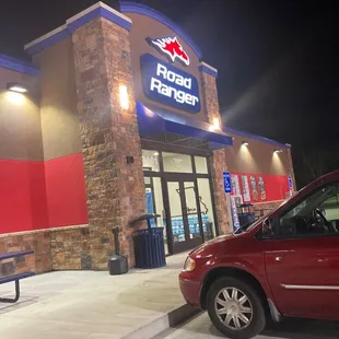 a red car parked in front of a road paper store