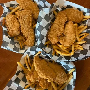 three baskets of fried chicken and french fries