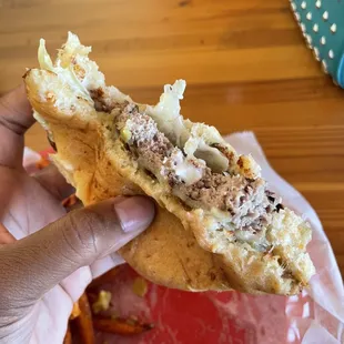 a hand holding a half eaten sandwich