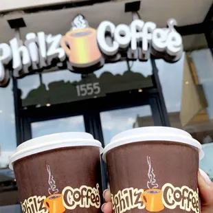 two cups of coffee in front of a coffee shop