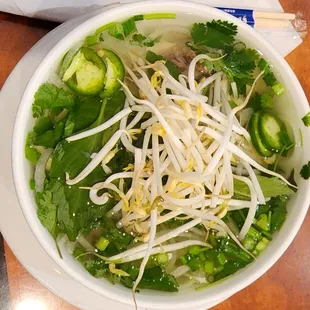 a bowl of pho with noodles and vegetables