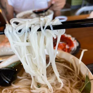 a bowl of noodles with chopsticks