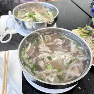 two bowls of soup and chopsticks on a table