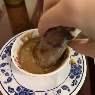 Dipping pork summer rolls in our peanut sauce
