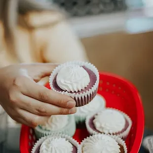 a woman holding a plate of cupcakes