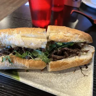 a beef sandwich on a plate with chopsticks