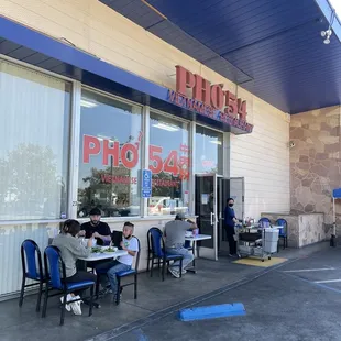 people sitting at tables outside a restaurant