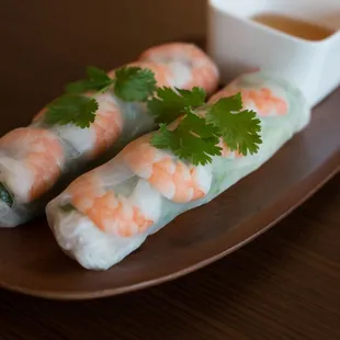 two rolls of shrimp and vegetables on a plate with dipping sauce