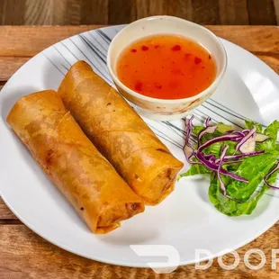 a plate of spring rolls and a bowl of dipping sauce