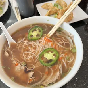 a bowl of soup with chopsticks