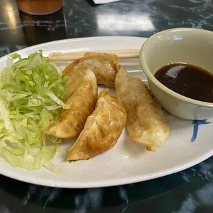 a plate of dumplings and a bowl of sauce