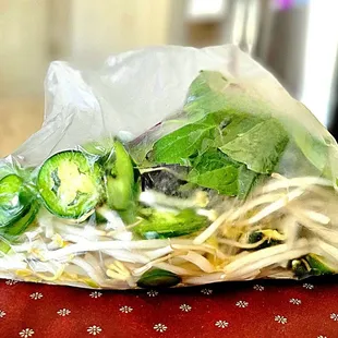 Carryout bean sprouts, basil leaves, sliced jalapeños, and lime.