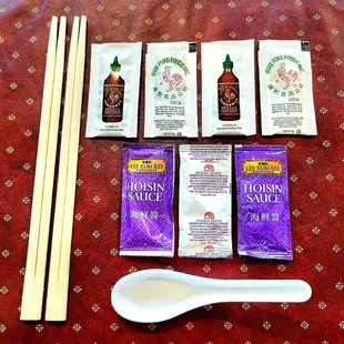Carryout orders of pho get chopsticks, plastic spoons, hoisin sauce, and sriracha sauce.