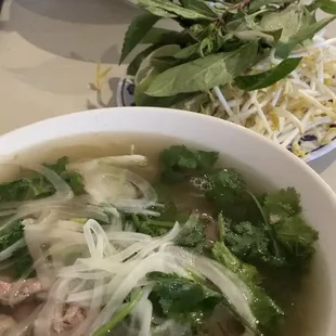 a bowl of pho with noodles and meat