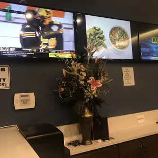 tvs on the wall and a vase of flowers
