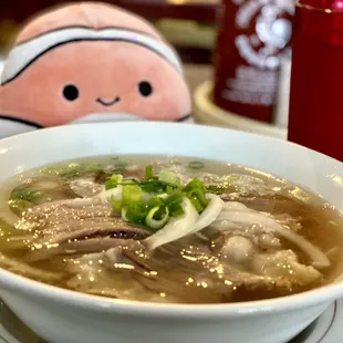 a bowl of soup with a stuffed animal in the background