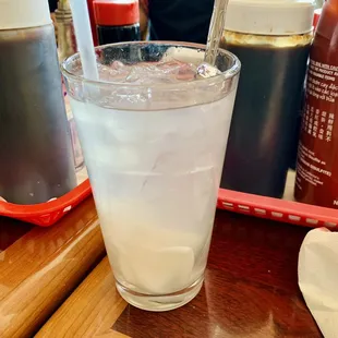 a glass of water with ice and a straw