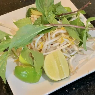 a white plate with a salad and lime